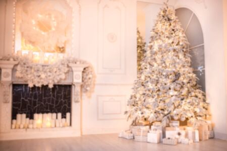 Blurred background christmas interior with New Year tree and artificial fireplace decorated light for holiday, white colorの写真素材