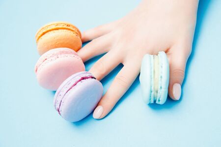 Beauty hand girl with trendy manicure taking color macaroons. Concept skin nail care, top viewの写真素材