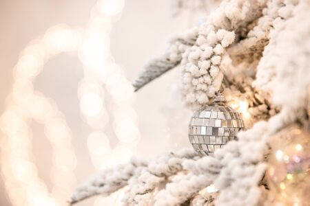 Christmas tree background with artificial snow decorated toys balls, snowflakes, branch golden illuminationの写真素材