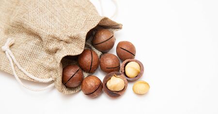 Pile macadamia nuts open kernels and shells in burlap bag on white background, top viewの写真素材