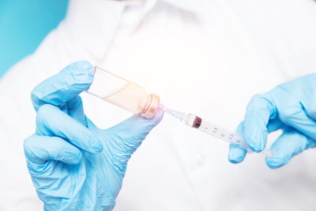 Doctor hand holding syringe and vaccine in blue gloves white coat. Disease injection concept.
