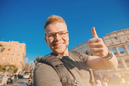 Happy man tourist with backpack with glasses taking selfie photo Colosseum in Rome, Italyの写真素材
