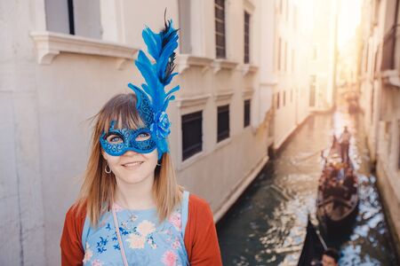 Portrait smiling young woman in Venice in Venetian blue mask background canal and gondolier. Concept travelの写真素材