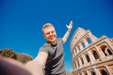 Happy young man making selfie in front of Colosseum in Rome, Italy. Concept travel tripの写真素材