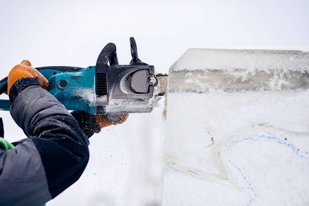 Ice sculpture carving man use electric chainsaw cut frozen winter.の写真素材