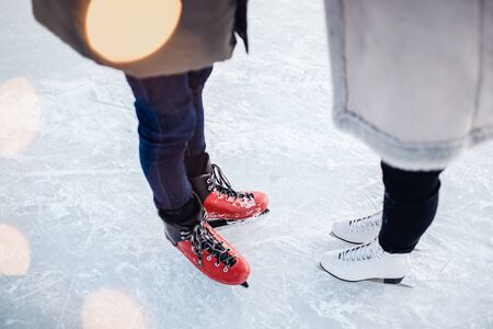 Skates guy and girl for walk on ice rink in winter, bokeh background, top view.の写真素材