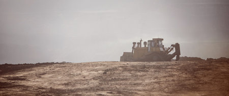 Excavator levels coal with iron bucket, grader paves road after detonation explosion in open mine