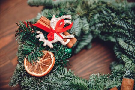 Closeup Christmas wreath from tree with decoration of white deer with red scarf and balls on wooden table. Top viewの写真素材