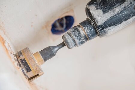 Builder man with pneumatic hammer drill perforator with diamond crown making hole in wall for electric cable, socket, switchの写真素材