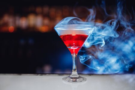 Red cocktail in martini glass with smoke, bartender drinks concept.の写真素材