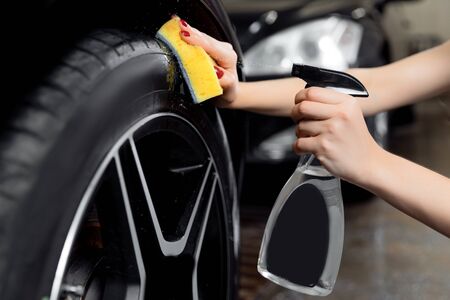 Car wash service, detailing using spray and sponge to wipe black tire.の写真素材