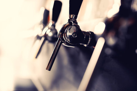 Beer taps raw in pub. Selective focus, dark background.