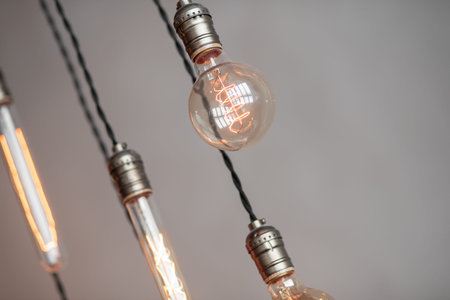 Edison retro lamp incandescent bulbs on gray plaster wall background in loft. Concept Vintage style....