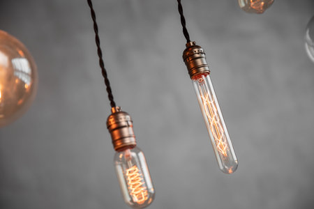 Edison retro lamp incandescent bulbs on gray plaster wall background in loft. Concept Vintage style....