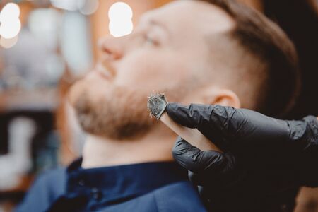 Master barber removes hair from nose of man with wax, depilation beauty procedure.の写真素材