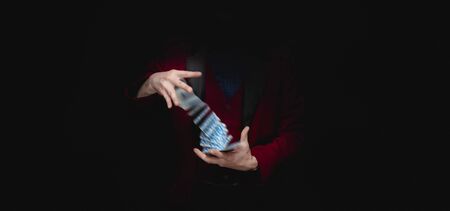 Magician shows trick with playing cards, dark backgroundの写真素材