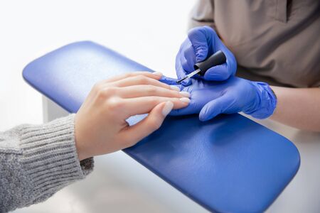 Master applies varnish drawing on nails gel in manicure salonの写真素材