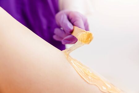 Beautiful woman having sugaring sweet depilation beauty treatment smooth thigh skin.の写真素材