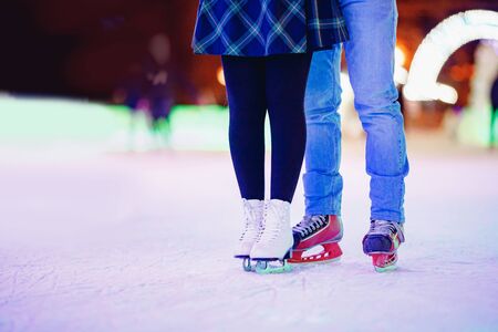 Ice skating lover couple having fun on snow winter holidays night illuminationの写真素材
