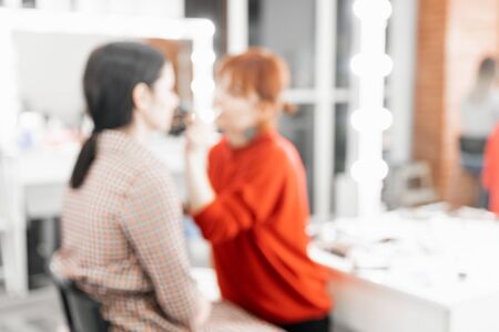 Blurred background beauty salon, master make-up artist, hairdresser girl working with clientの写真素材