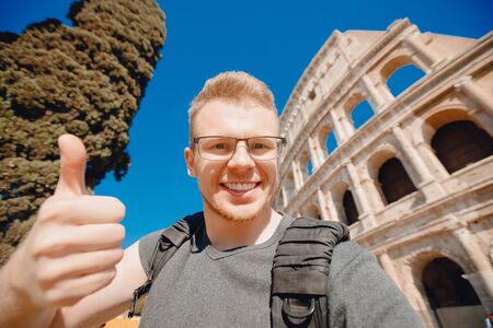 Happy man tourist with backpack with glasses taking selfie photo Colosseum in Rome, Italyの写真素材