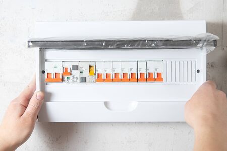 Electrician mounts consumer electric switchboard control panel for home enclosure for distribution and power electricity.の写真素材