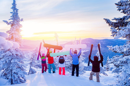 Happy team of snowboarders and skier having fun tossing snow. Light sun in winter forest sunriseの写真素材