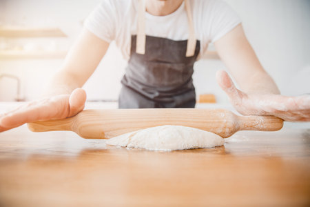 Banner Male baker prepares dough with hands for baking bread, wooden table white backgroundの写真素材