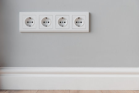 White European sockets on gray concrete wall in loft style, with high polyurethane baseboard