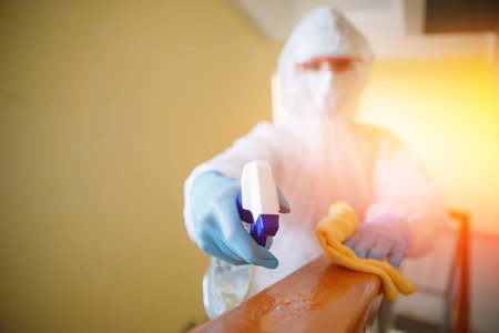 Concept coronavirus disinfection. People in hazmats making cleaning railing of stairs apartment...