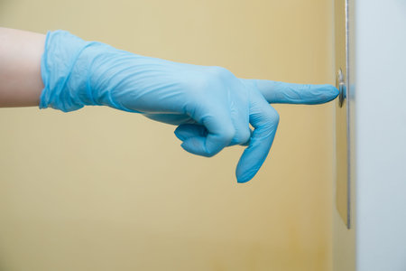 Woman presses elevator button in protective medical glove. Concept coronavirus disinfection