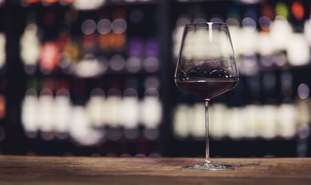 Glass of red wine on wooden bar counter in restaurant, copy spaceの写真素材
