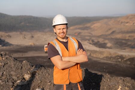 Engineer smiling man in white helmet on background open pit mine industryの写真素材