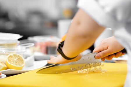 Hands woman chef cut knife with garlic and onion on cutting board closeupの写真素材