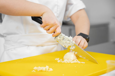 Hands woman chef cut knife with garlic and onion on cutting board closeup