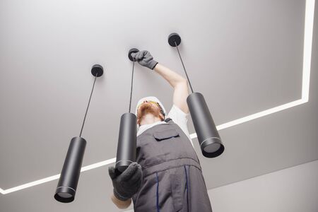 Electrician worker installation electric lamps light inside apartment. Construction decoration concept.の写真素材