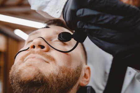 Spa and skin care for men. Barber professional applies black charcoal mask to client man.の写真素材