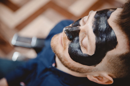 Spa facial skin care for men, applying removal of black charcoal mask from nose face in barbershop.の写真素材