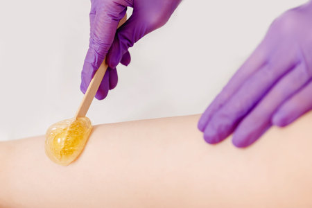 Beautiful woman having sugaring sweet depilation beauty treatment smooth thigh skin.