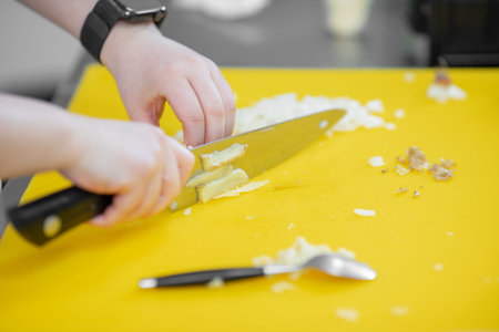 Hands woman chef cut knife with garlic and onion on cutting board closeup