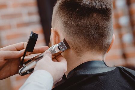 Hairdresser cuts hair men in barbershop. Barber doing correct beard trim electric shaver.の写真素材