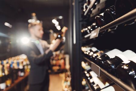 Bartender sommelier takes bottle of red wine from counter of restaurant drinks store.の写真素材