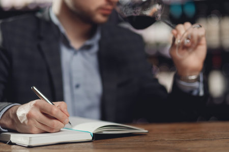 Sommeliers male tasting red wine and making notes aroma degustation card.の写真素材