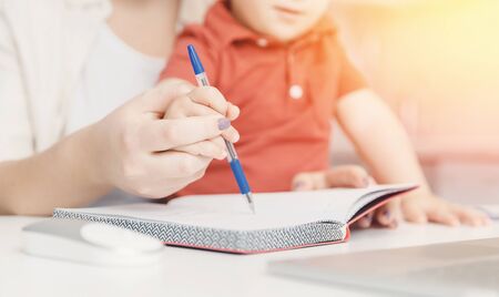 Mother teaching her kid son how to write pen. concept Online learning quarantineの写真素材