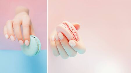 Beautiful girl hands with trendy manicure nail holding pink macaroon cake through hole in backgroundの写真素材