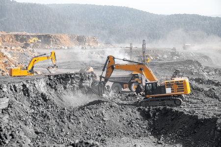 Open pit mine industry. Excavator work loading of coal into Yellow mining truck.