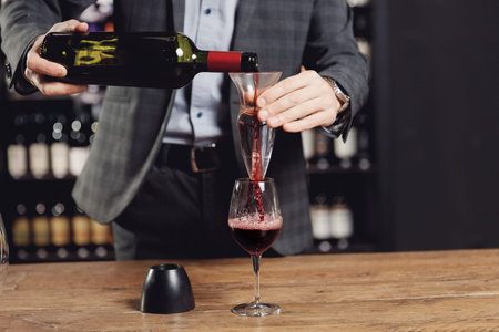 Sommelier pouring red wine into bottle decanter glass to make aeration drink