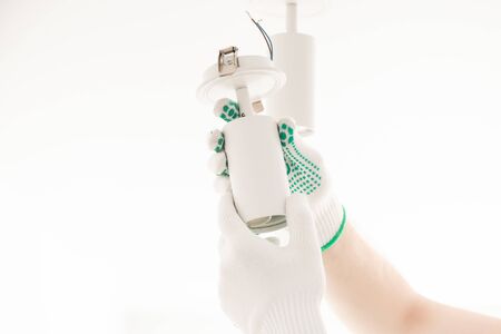 Electrician worker man assembling electric lamps in new apartment.の写真素材