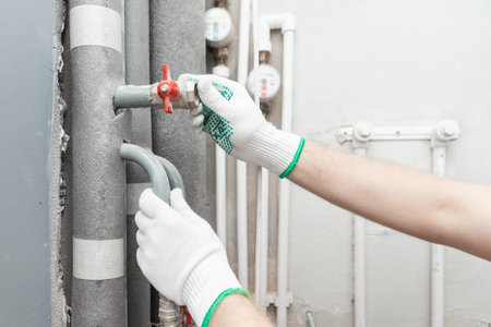 Male plumber checks pipes for central hot and cold water supply of apartment.
