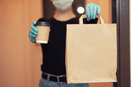 Food and coffee delivery cardboard boxes woman in protective mask. Quarantine coronavirus online shopping.の写真素材